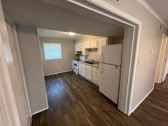 a kitchen with a refrigerator a stove top oven and wooden floor