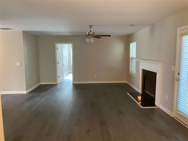 an empty room with wooden floor fireplace and windows