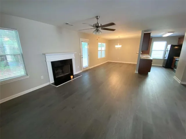 an empty room with wooden floor fireplace and windows