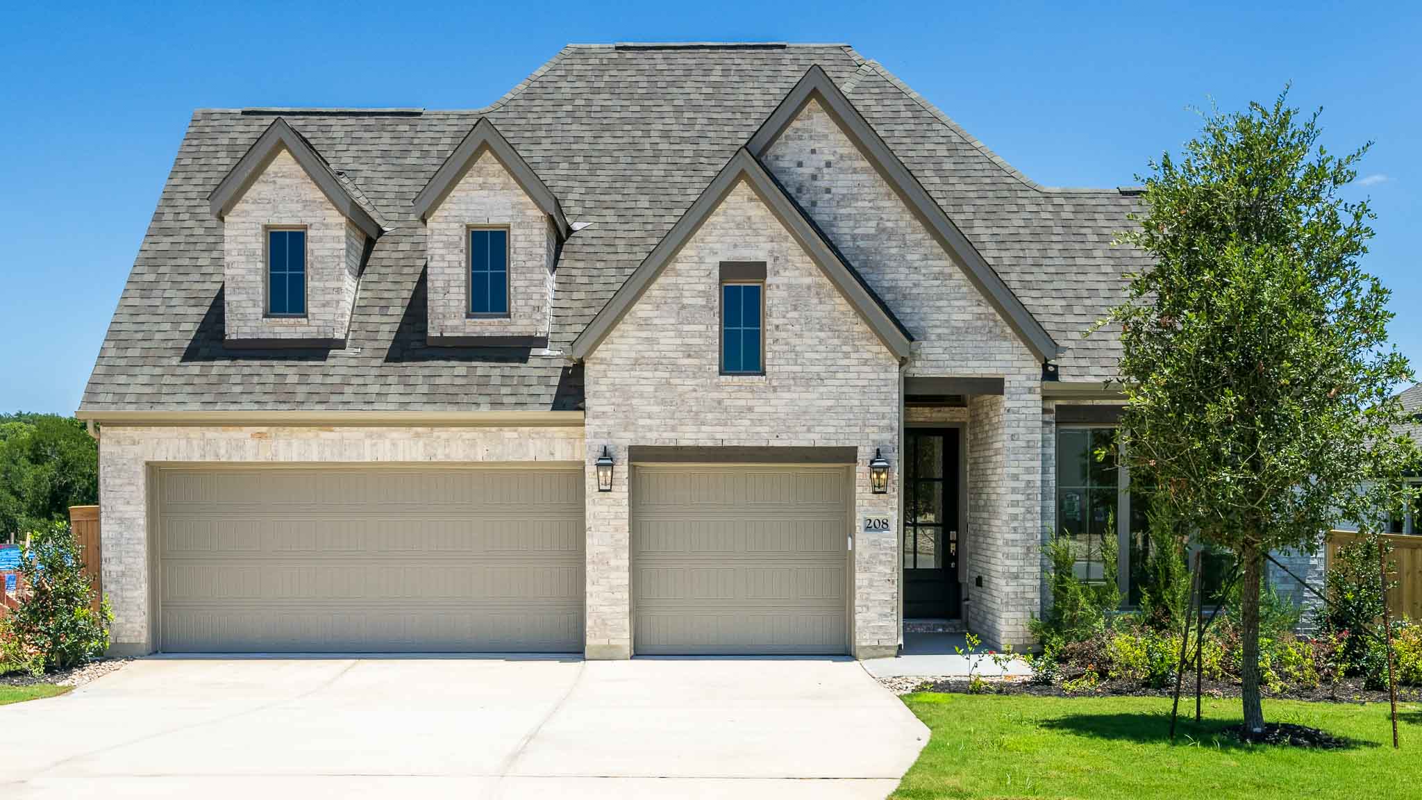 View of front facade featuring a shingled roof, driveway, an attached garage, and a front yard
