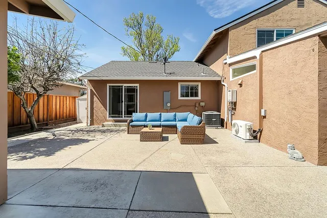a view of a patio with couches and table and chairs with wooden fence and plants