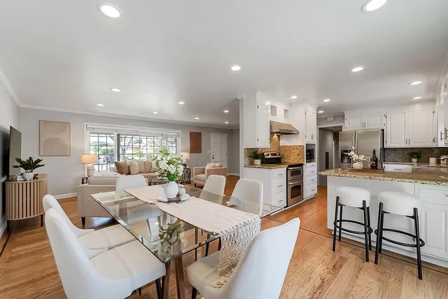 a living room with stainless steel appliances kitchen island granite countertop a dining table chairs and a kitchen view