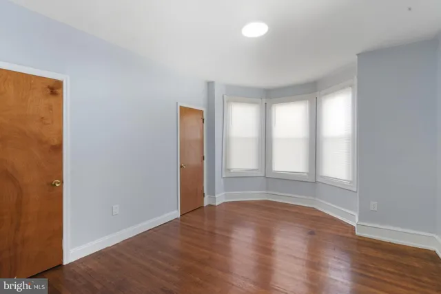 a view of an empty room with wooden floor and closet