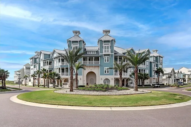 a front view of multi story residential apartment building with yard and sign board