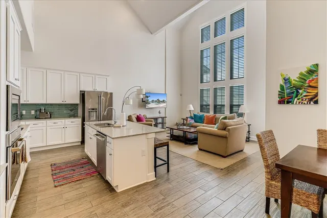 a open kitchen with stainless steel appliances granite countertop a stove top oven a refrigerator a dining table and chairs with wooden floor