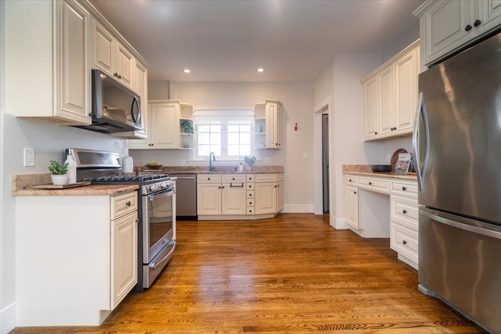 132 Church Street, Unit 1 Waltham, MA 02452 - Photo 10 of 42 a kitchen with stainless steel appliances granite countertop a refrigerator stove a sink and dishwasher with wooden floor