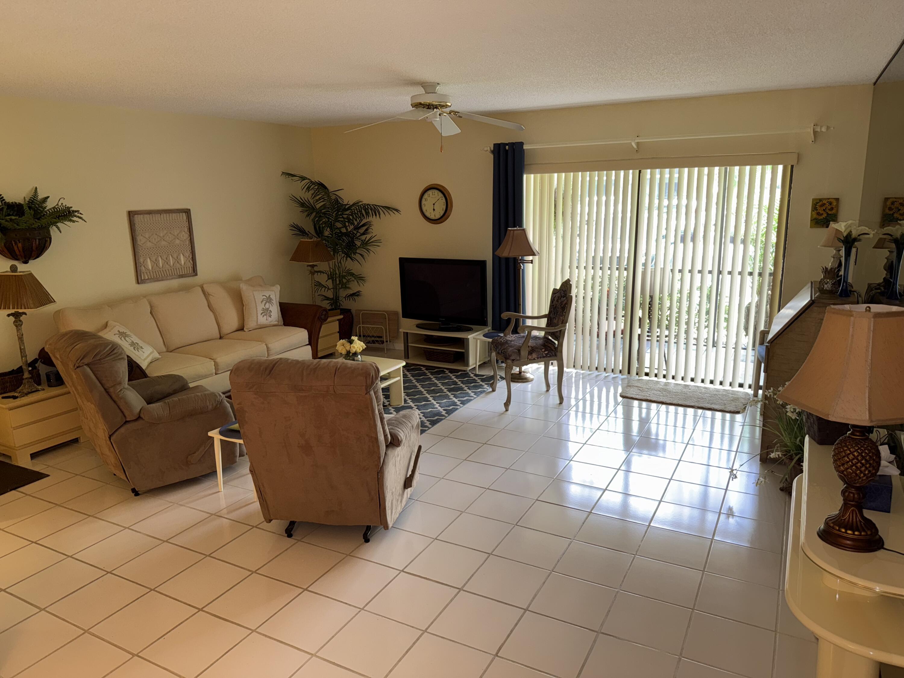 147 Deer Creek Boulevard, Unit 402 Deerfield Beach, FL 33442 - Photo 23 of 81 a living room with furniture a flat screen tv and a large window