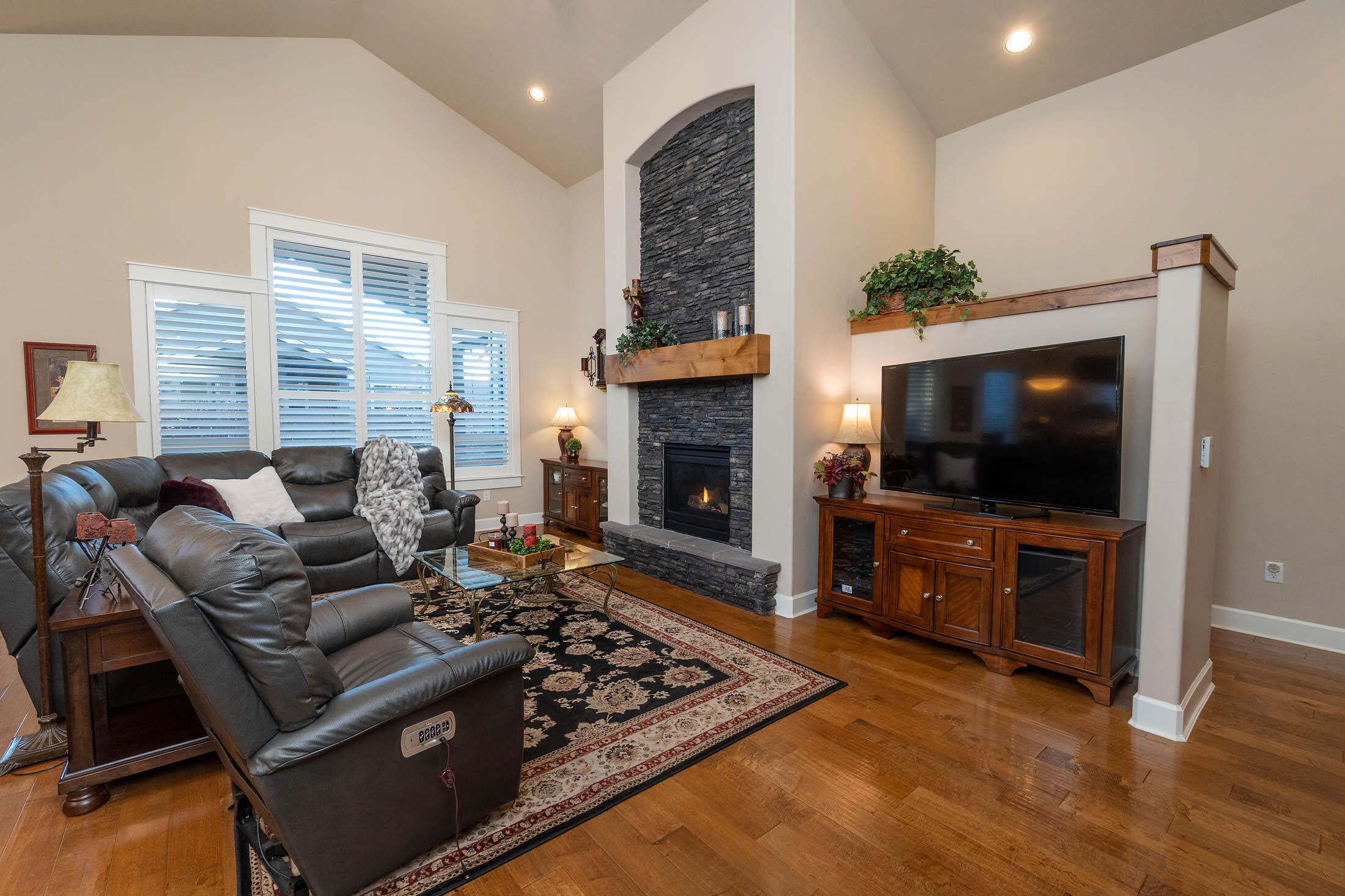 61129 Manhae Loop Bend, OR 97702 - Photo 7 of 44 Greatroom gas fireplace with upgraded stone extending above stained mantle. Upgraded stained trim on tall pony wall hall leading to primary suite (right-side of photo).