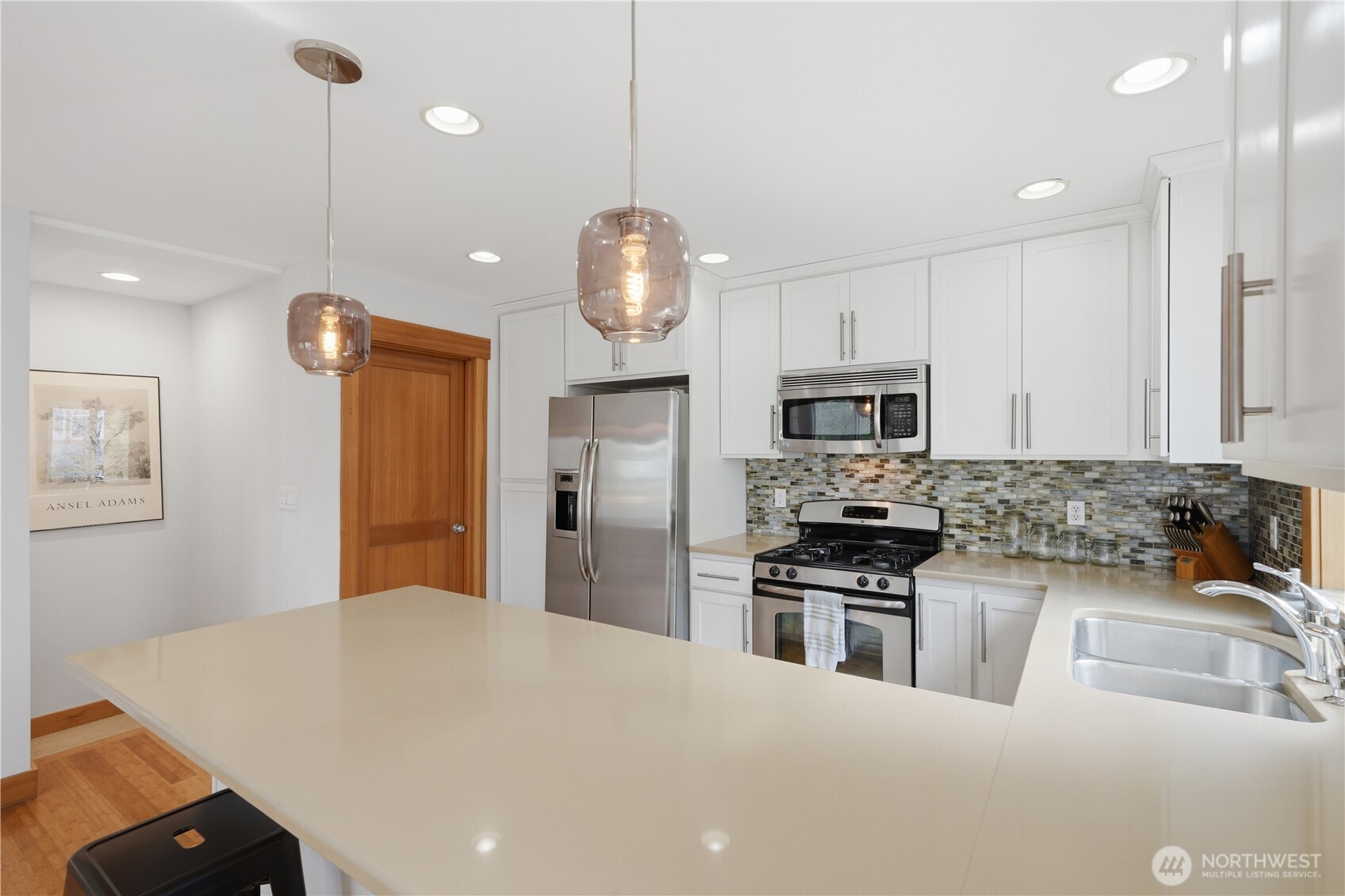 4037 7th Avenue Northeast, Unit A Seattle, WA 98105 - Photo 17 of 35 a kitchen with stainless steel appliances granite countertop a sink dishwasher a refrigerator a microwave oven a stove and white cabinets with wooden floor