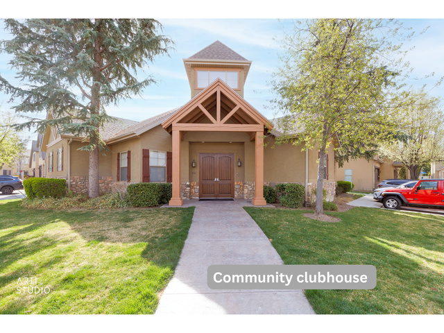 6761 950 East Midvale, UT 84047 - Photo 29 of 44 Community clubhouse featuring a stucco exterior, stone base accents, a prominent covered entry with exposed wood beams, and a central tower with upper-level windows
