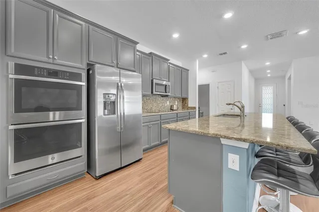 a kitchen with stainless steel appliances granite countertop a refrigerator stove and sink