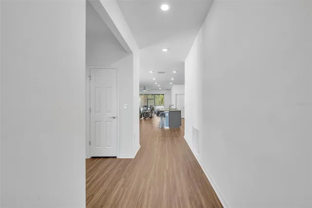 a view of a hallway with wooden floor and a bathroom