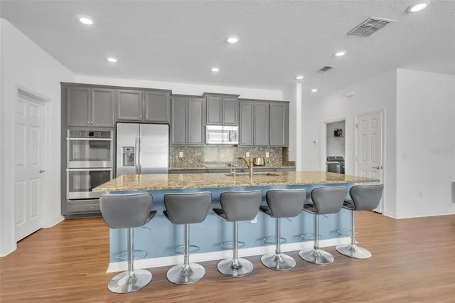a kitchen with a dining table chairs and wooden floor