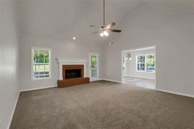an empty room with windows and fireplace