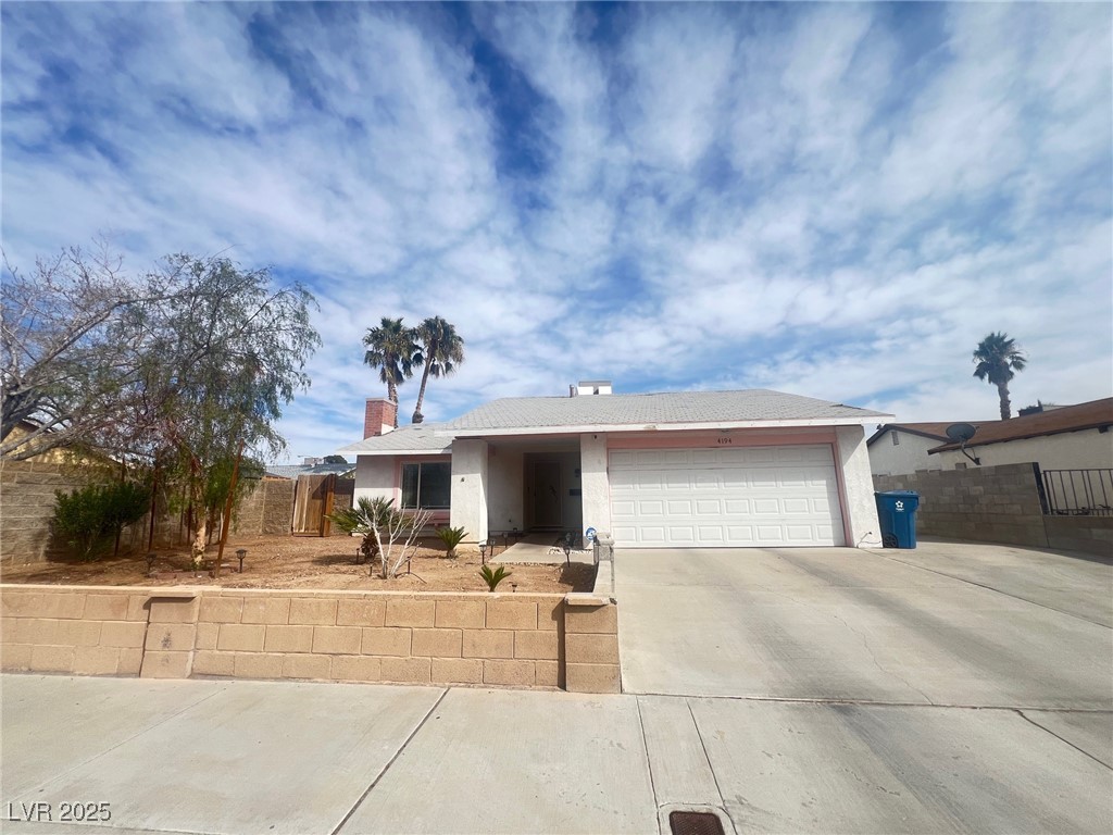 Ranch-style home featuring a chimney, a garage, concrete driveway, and stucco siding