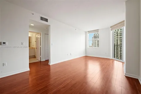 an empty room with wooden floor cabinet and windows