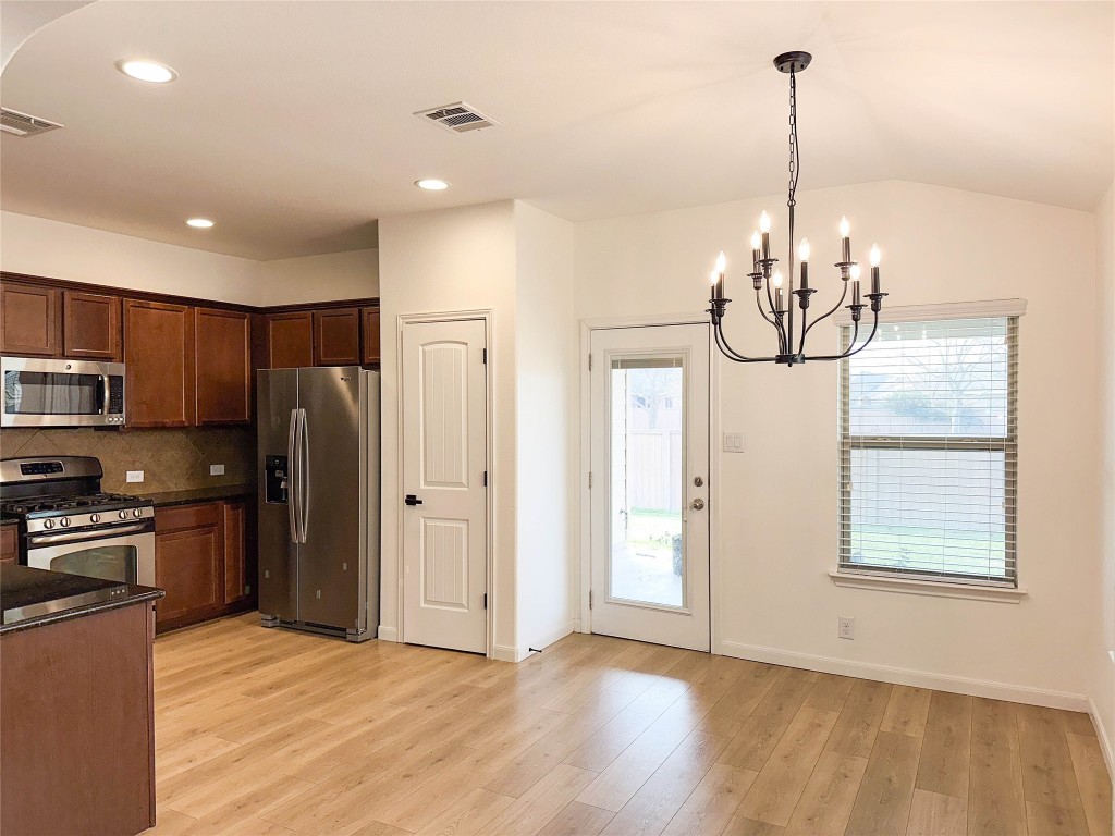1437 April Meadows Loop Georgetown, TX 78626 - Photo 8 of 27 a view of a kitchen with stainless steel appliances granite countertop a refrigerator a stove and a wooden floors