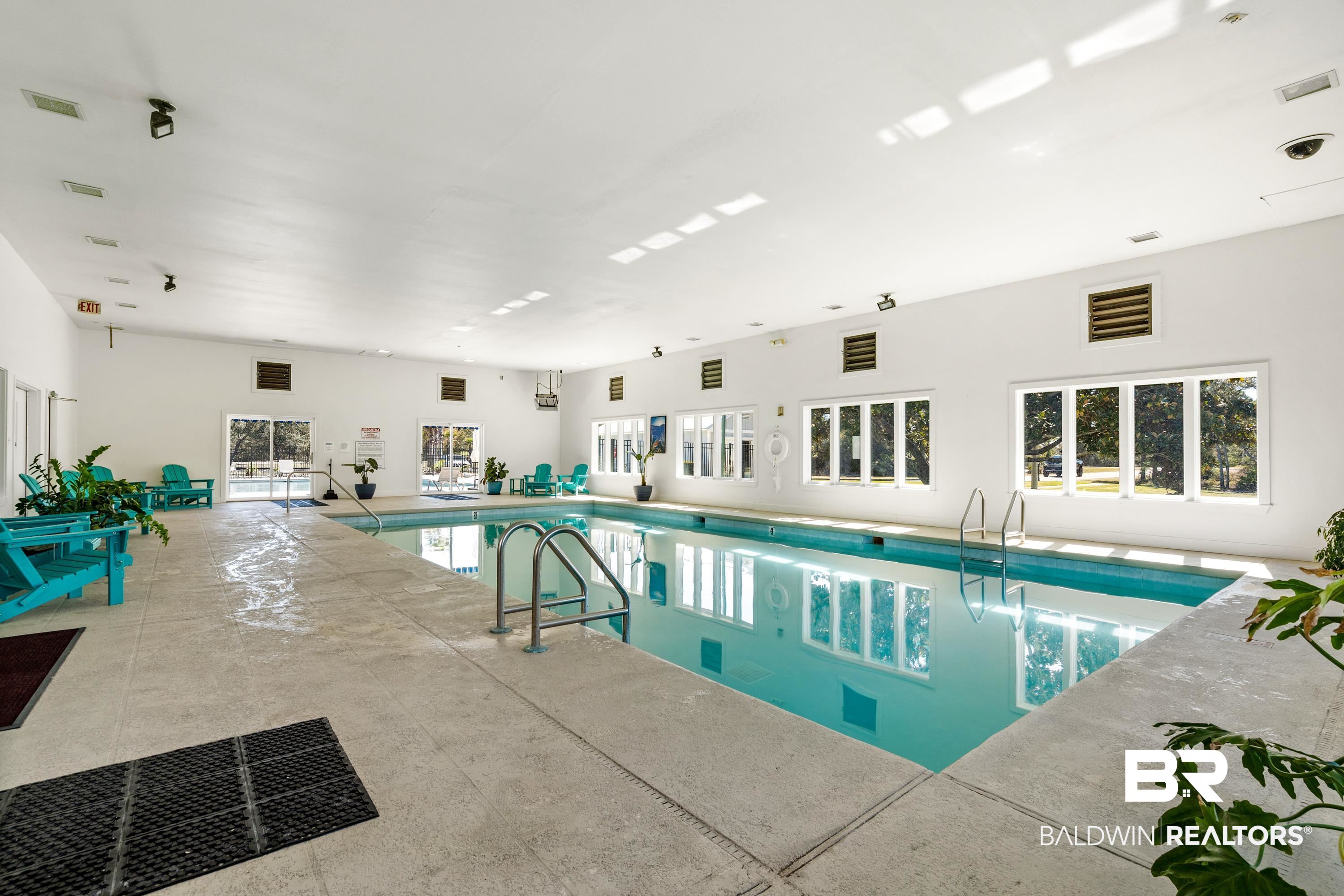 30194 River Road Orange Beach, AL 36561 - Photo 42 of 45 Indoor swimming pool featuring light blue water, light-colored surrounding deck, multiple large windows, and overhead lighting