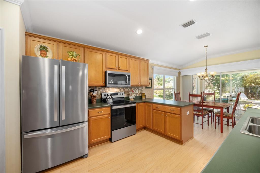 12309 Southeast 92nd Court Road Summerfield, FL 34491 - Photo 26 of 81 a kitchen with stainless steel appliances granite countertop a refrigerator a stove a sink a dining table and chairs with wooden floor