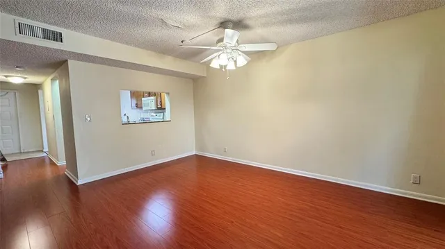 an empty room with wooden floor chandelier fan and windows