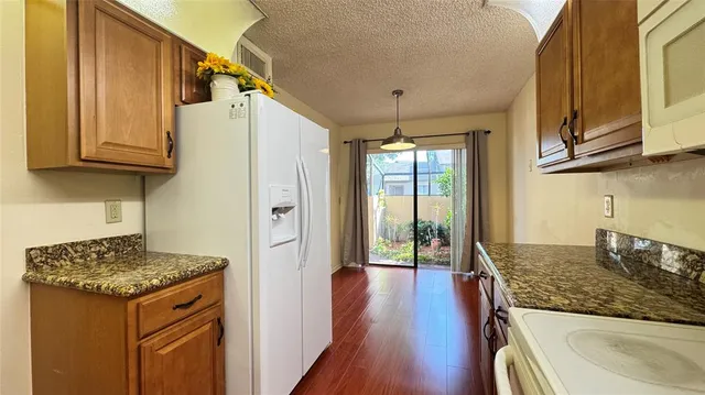 a kitchen with granite countertop a sink stove and refrigerator