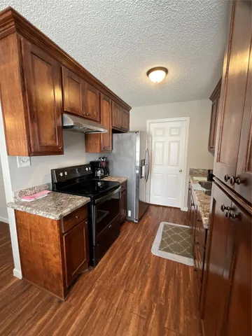 a kitchen with granite countertop stainless steel appliances a stove top oven and cabinets