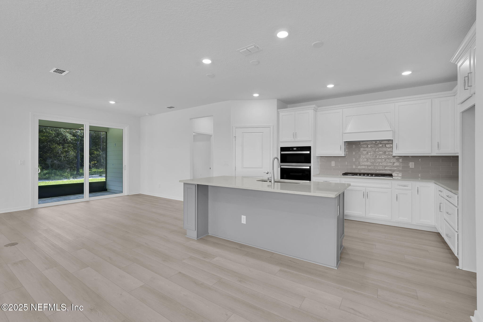 134 Headstream Drive St. Johns, FL 32259 - Photo 6 of 28 a open kitchen with kitchen island a sink dishwasher stove and white cabinets with wooden floor