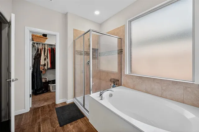 a spacious bathroom with a bathtub double sink and mirror
