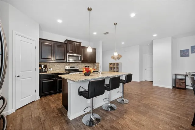 a kitchen with kitchen island granite countertop a sink cabinets and stainless steel appliances