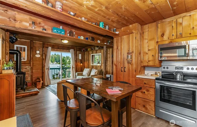 a kitchen with stainless steel appliances granite countertop a stove a refrigerator a kitchen island a table and chairs with wooden floor