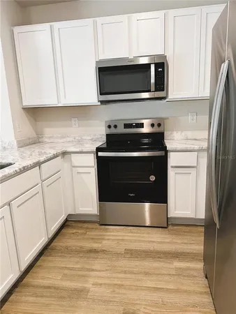 a utility room with granite countertop a sink and dishwasher a stove with wooden floor