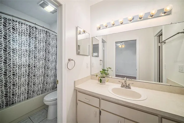 a bathroom with a granite countertop toilet a sink a mirror a shower and a mirror