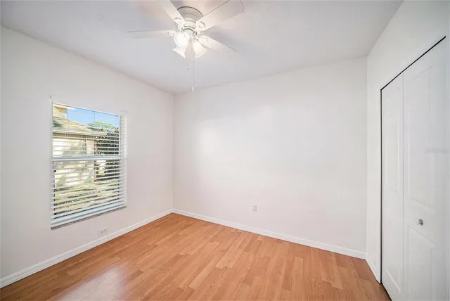 a view of empty room with wooden floor and fan