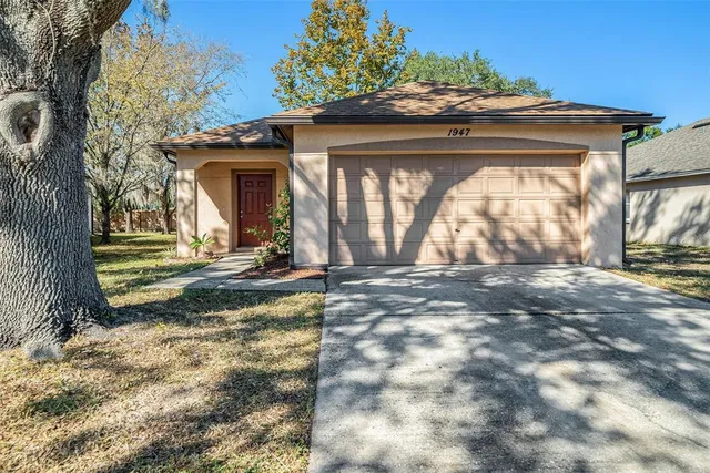 a view of a house with a small yard and large tree
