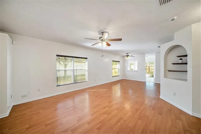 a view of an empty room with a window and wooden floor