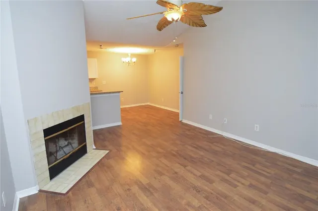 a view of an empty room with wooden floor and a ceiling fan