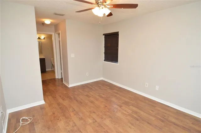 an empty room with a window and a ceiling fan