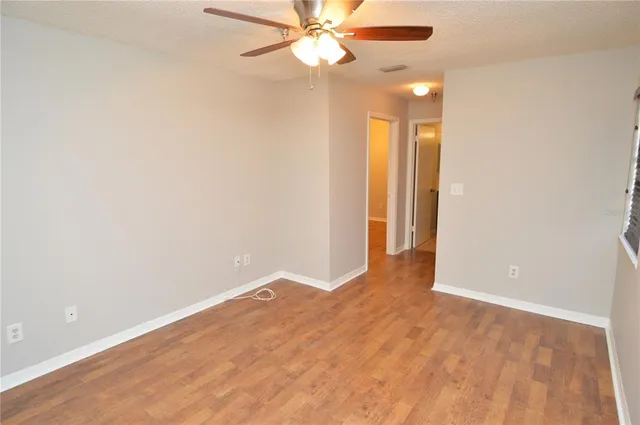 a view of a room with wooden floor and a ceiling fan