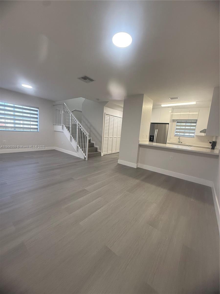 6752 Northwest 182nd Street, Unit 101 Hialeah, FL 33015 - Photo 1 of 23 an empty room with wooden floor and windows