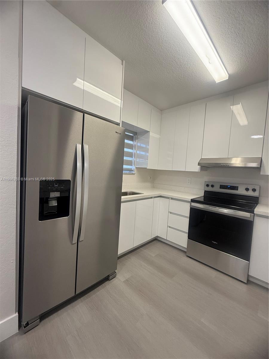 6752 Northwest 182nd Street, Unit 101 Hialeah, FL 33015 - Photo 4 of 23 a kitchen with stainless steel appliances a refrigerator sink and cabinets