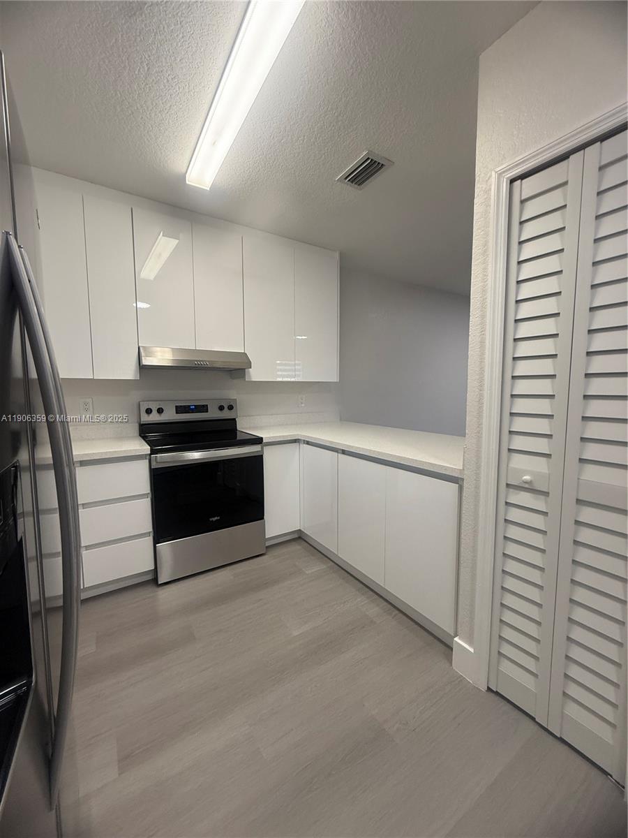 6752 Northwest 182nd Street, Unit 101 Hialeah, FL 33015 - Photo 6 of 23 a kitchen with stainless steel appliances a refrigerator and white cabinets