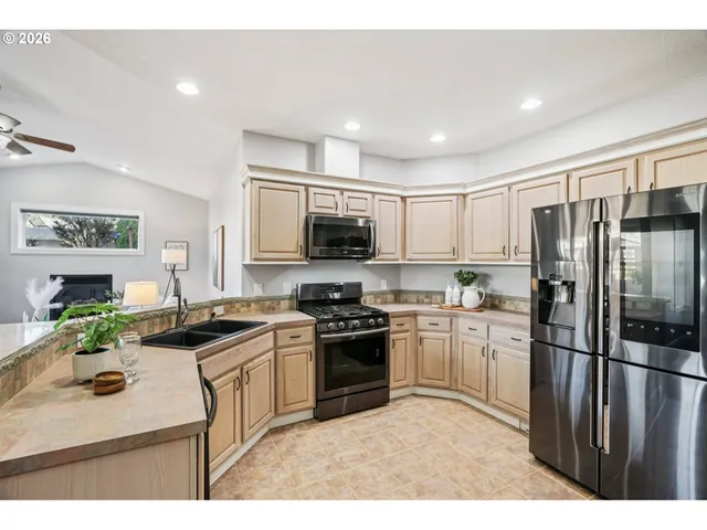 a kitchen with stainless steel appliances a stove a sink a microwave a kitchen island and chairs