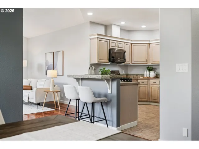 a living room with stainless steel appliances kitchen island granite countertop furniture a rug kitchen view and a chandelier