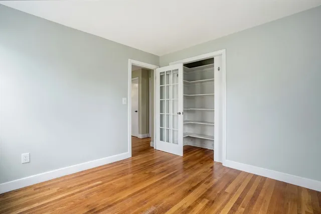 a view of an empty room with wooden floor and closet