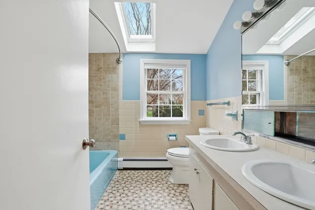 a bathroom with a sink a toilet a mirror a window and shower