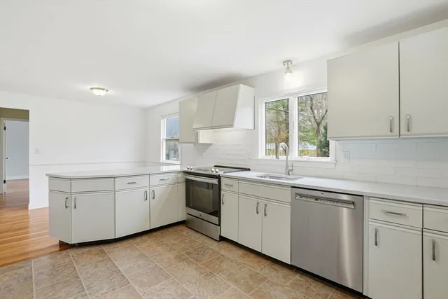 a kitchen with white cabinets appliances a sink and a window