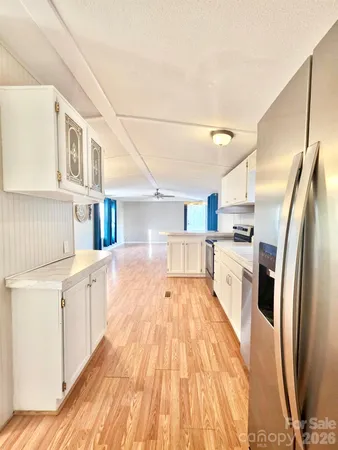a large white kitchen with kitchen island a large counter top space and stainless steel appliances
