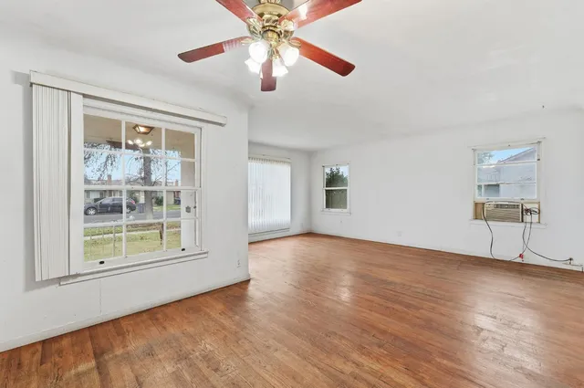 a view of an empty room with a window and wooden floor