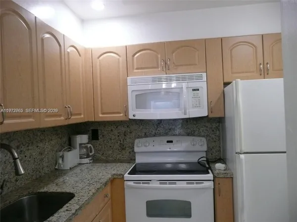 a kitchen with granite countertop a sink stove and refrigerator