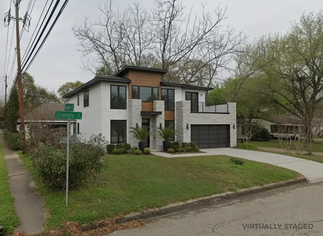 a front view of a house with a garden and trees